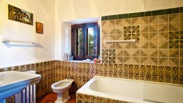 Un bagno con una vasca, un water e un lavandino. Si vede una finestra con vista sull'esterno.