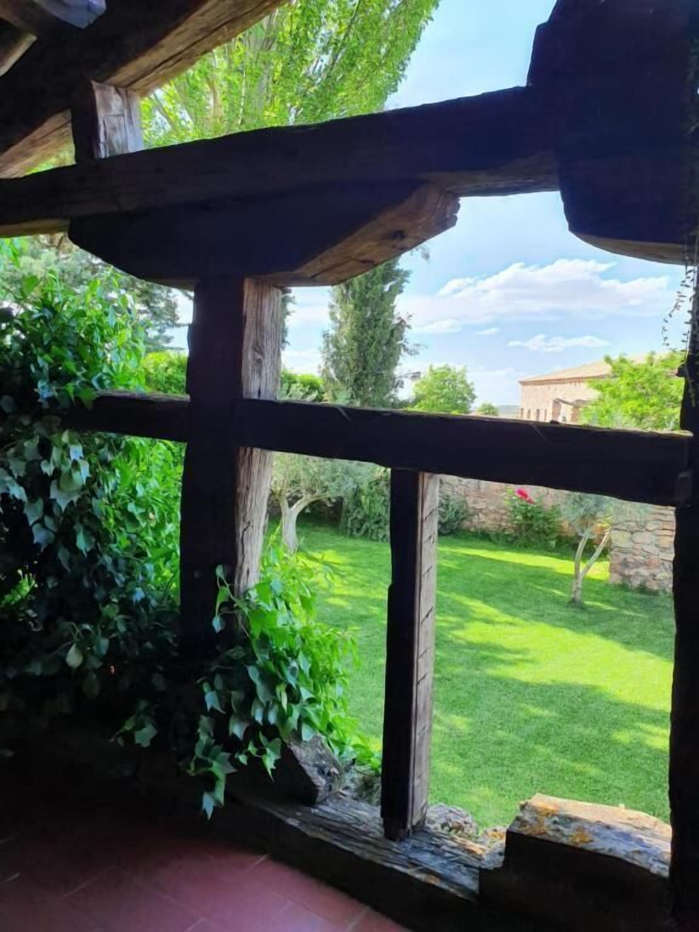 A rustic wooden structure with a view of a well-maintained garden and a distant building.
