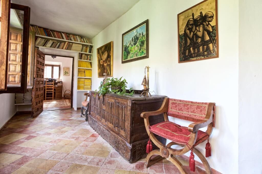 A hallway with a wooden bench, a bookshelf, and a door leading to another room.