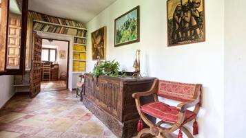A hallway with a wooden bench, a bookshelf, and a door leading to another room.