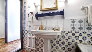 Une salle de bain avec un lavabo blanc, un miroir, un porte-serviettes et des carreaux à motifs.