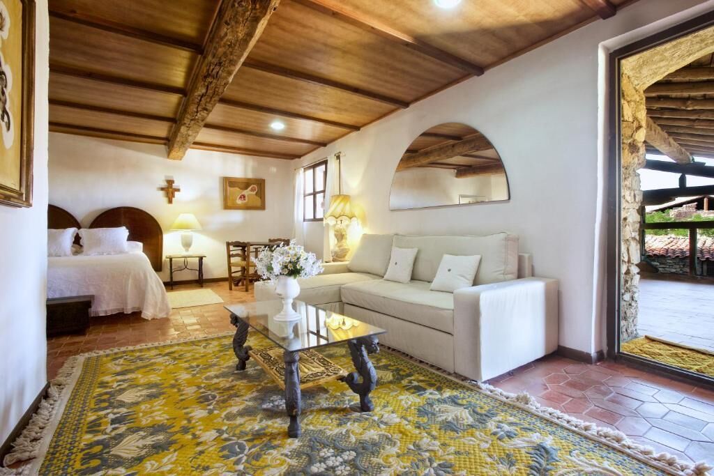 Un ambiente accogliente con un letto, un divano, un tavolino da caffè e un grande specchio.