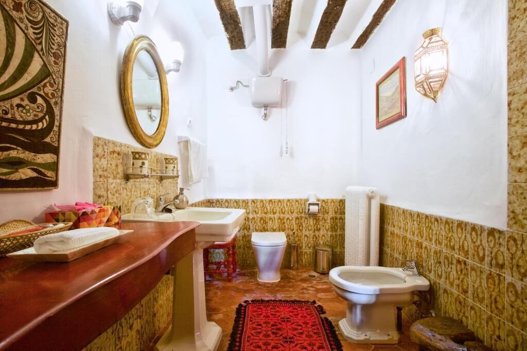 Une salle de bain avec un meuble-lavabo en bois, un lavabo, des toilettes et un bidet.