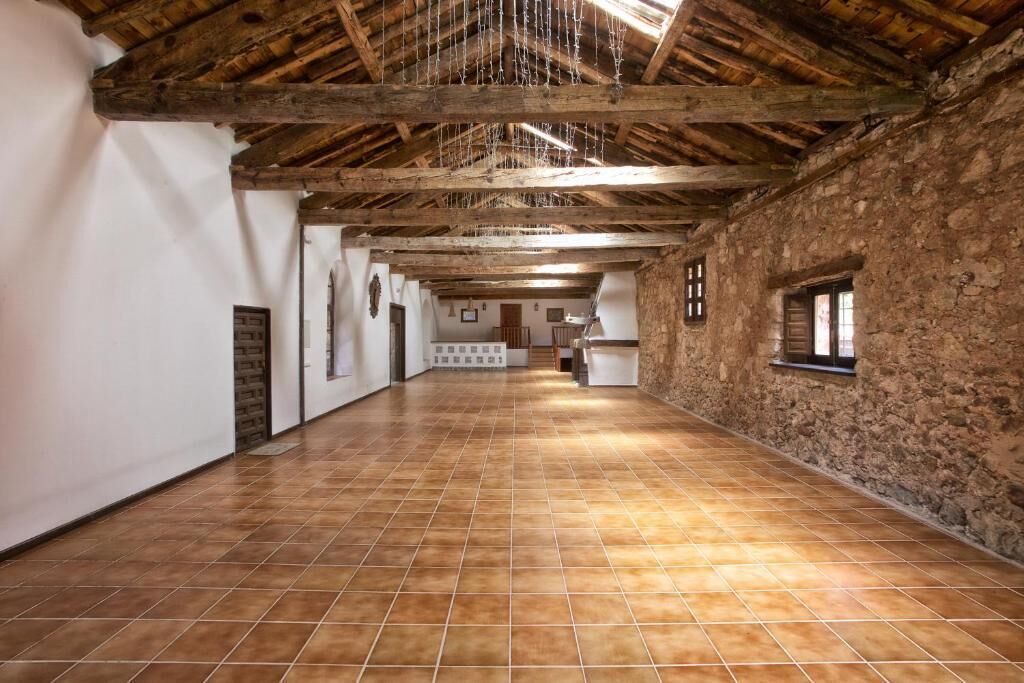 Ein geräumiger Saal mit hoher Holzbalkendecke und Steinwänden.