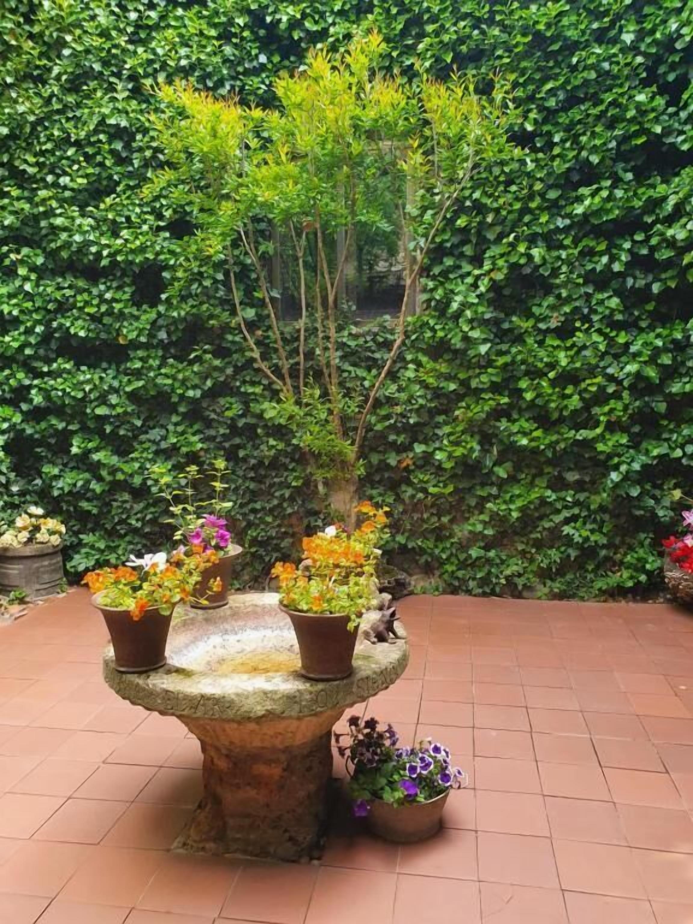 A stone planter table with various potted plants and flowers.