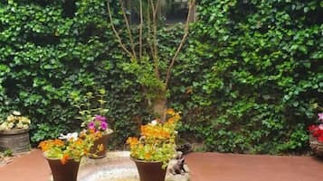 A stone planter table with various potted plants and flowers.