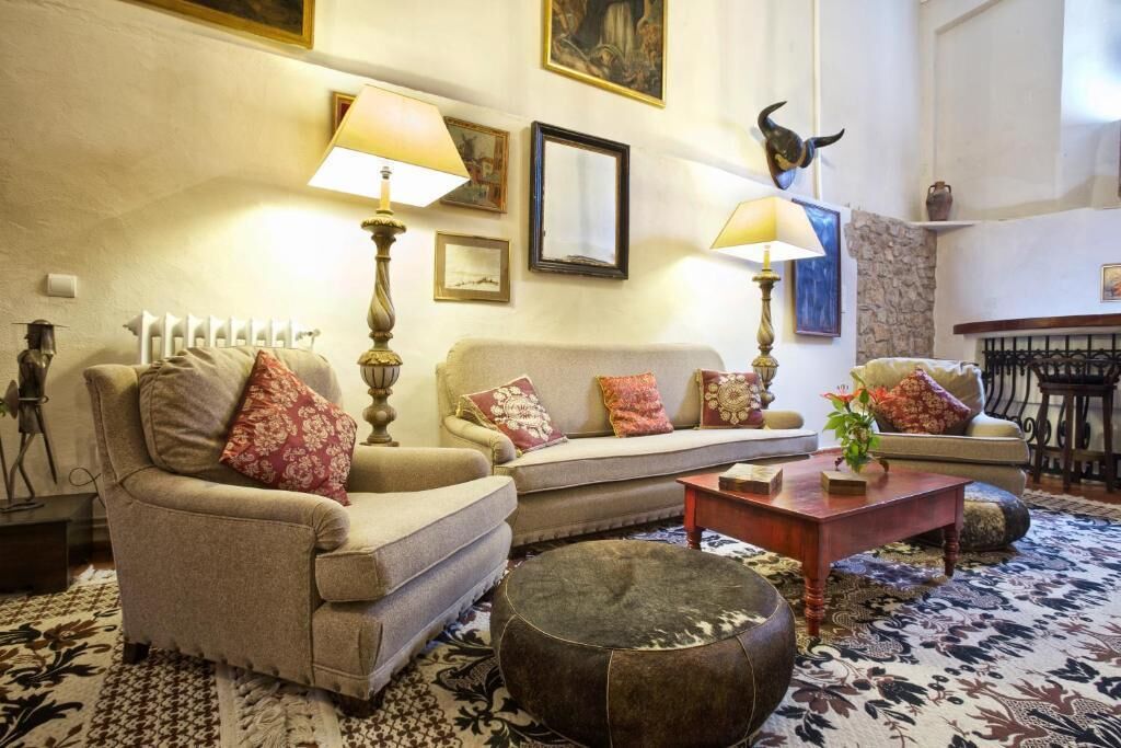 A cozy living room with a sofa, armchairs, a coffee table, and a patterned rug.
