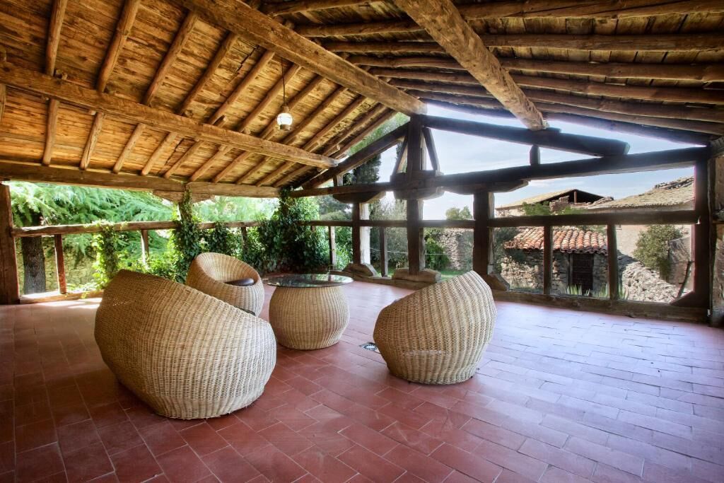 A covered outdoor seating area with wicker furniture and a view of the surrounding landscape.