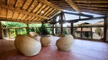 A covered outdoor seating area with wicker furniture and a view of the surrounding landscape.