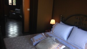 Ein Hotelzimmer mit einem Bett, einem Nachttisch mit Lampe und Blick durch ein Fenster nach draußen.