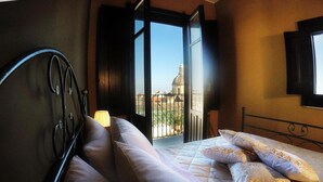 Ein Schlafzimmer mit Bett, Kissen und einem Fenster mit Blick auf Gebäude.