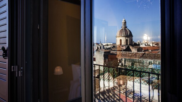 Blick von einem Balkon mit Metallgeländer auf ein historisches Gebäude mit Kuppel und Kirchturm.