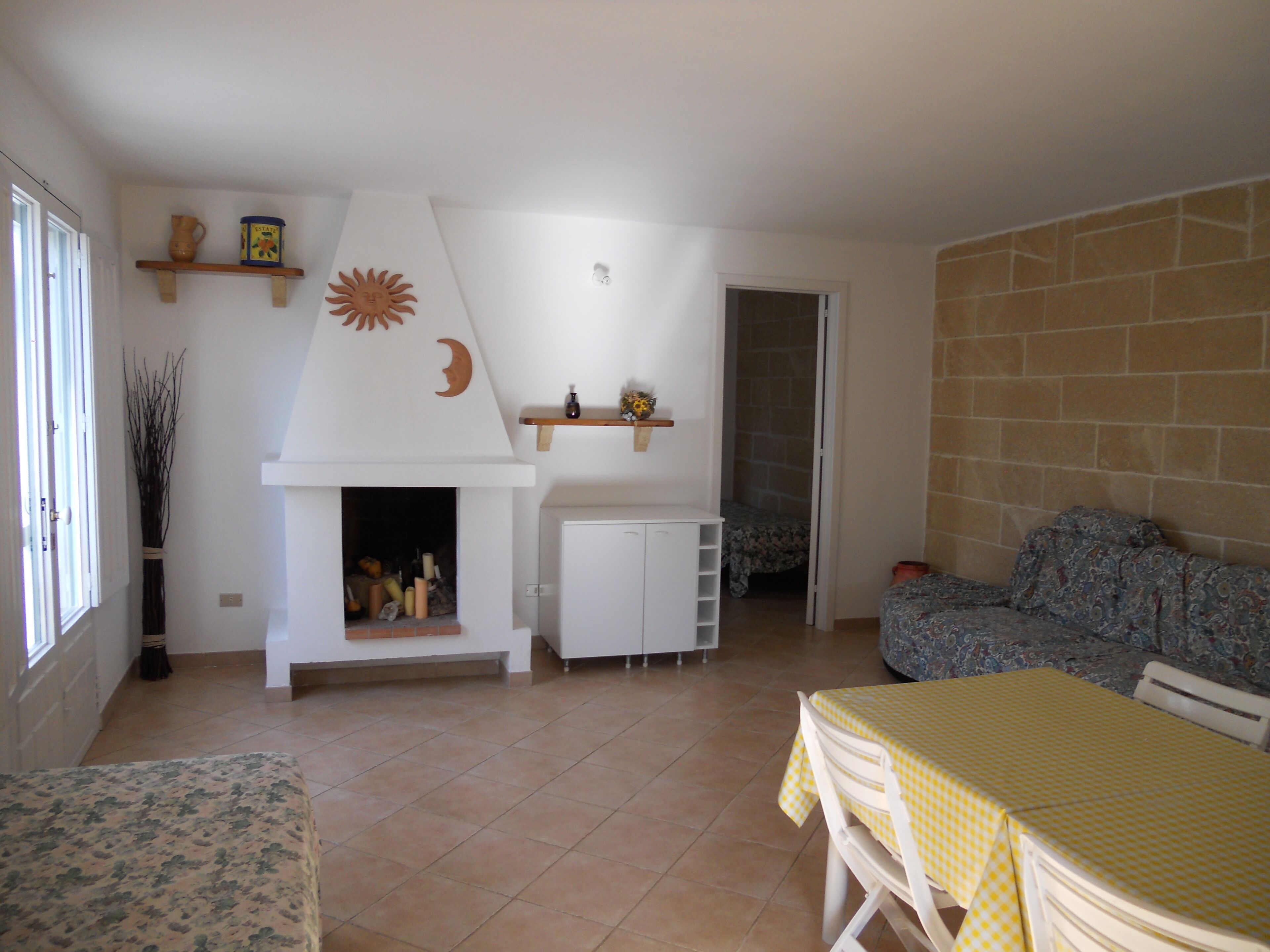 Una sala de estar con chimenea, un sofá, una mesa de comedor y una zona de cocina.