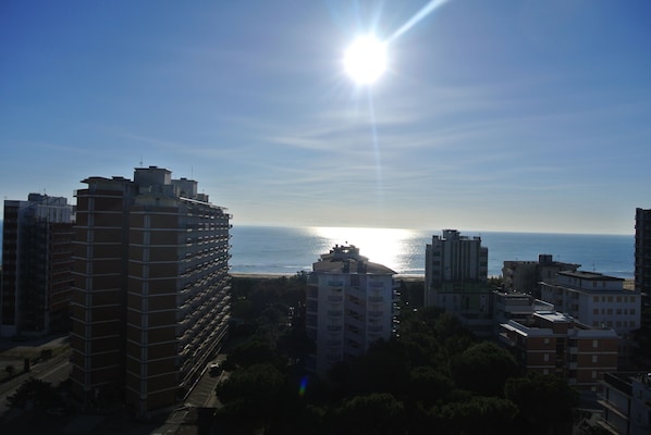 A high-rise building with multiple floors and balconies, overlooking a body of water.