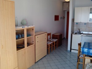 Une cuisine de taille réduite, avec des meubles de rangement en bois, une petite table et des chaises.