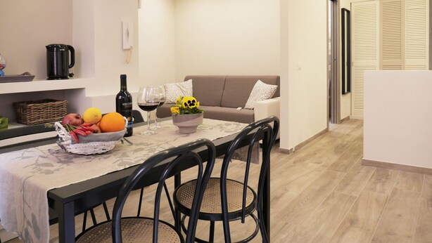 Een moderne keuken met een eettafel, stoelen, een koffiezetapparaat en een fruitschaal.