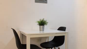 Una mesa blanca con dos sillas negras y una planta en maceta encima.
