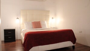 Een slaapkamer met een bed, nachtkastje, kledingkast en een airconditioning.