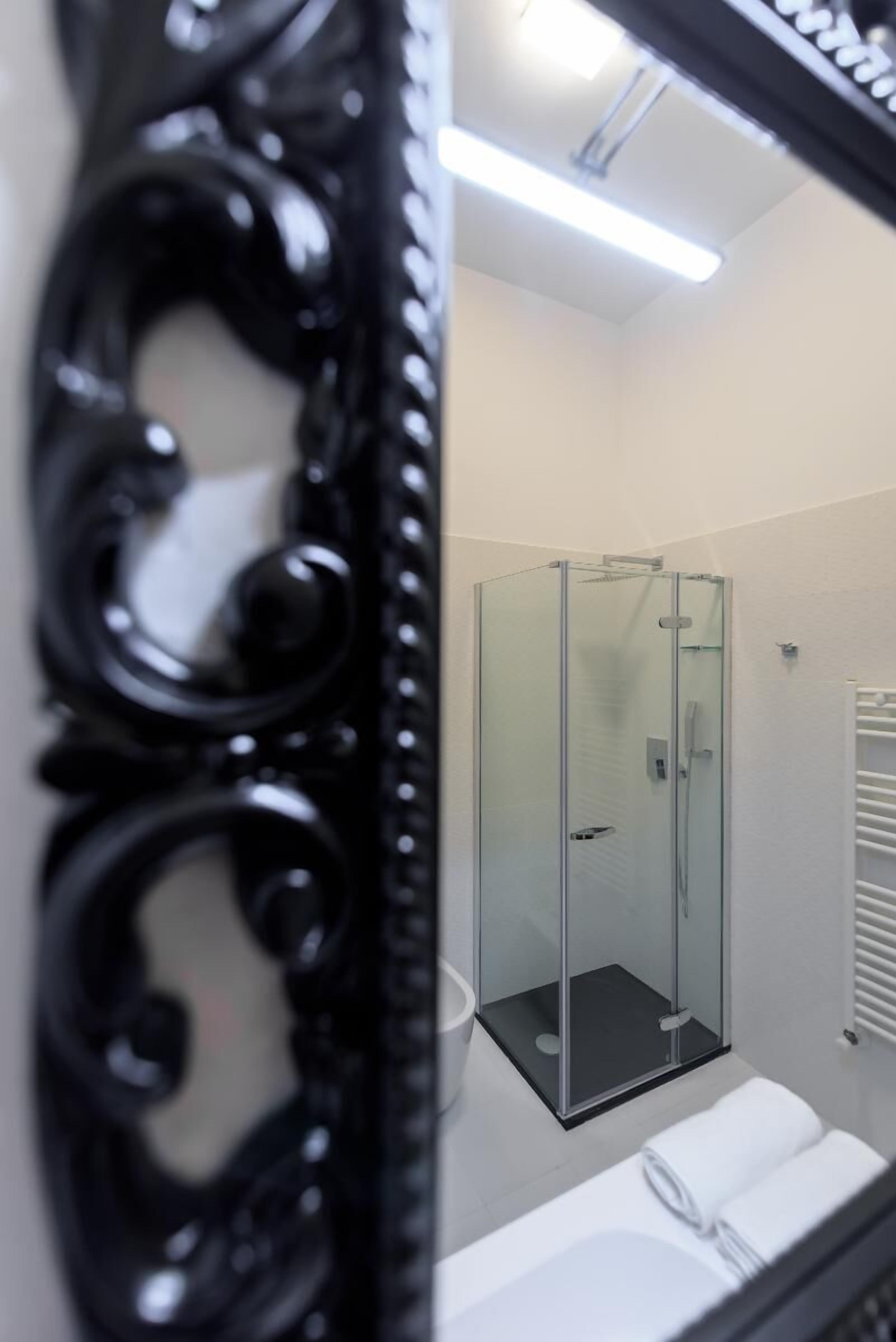 Uma casa de banho moderna com cabine de duche em vidro, lavatório branco e toalha sobre o balcão.