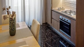 Une cuisine moderne équipée d’une cuisinière à gaz, d’un four et de plans de travail en marbre. On y trouve également un coin repas avec une table et des chaises, ainsi qu’un vase contenant des fleurs séchées.