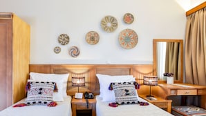 Hotelkamer met twee bedden, een houten hoofdbord, een bureau, een stoel, een spiegel en decoratieve wandplaten.