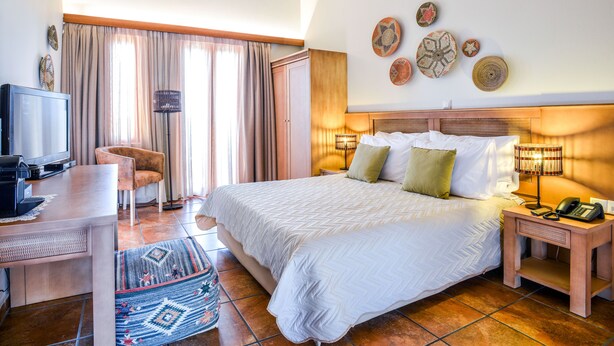 Een hotelkamer met een bed, een bureau, een televisie en een stoel.