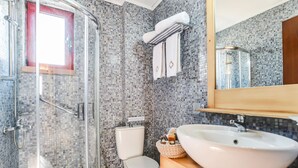 Een badkamer met een douchecabine van glas, een toilet en een wastafel met een spiegel erboven.