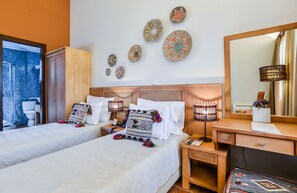 Ein Hotelzimmer mit zwei Betten, einem großen Spiegel, Wanddekoration, einem Schreibtisch mit Lampe und Blick ins Badezimmer.