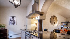 A modern kitchen with stainless steel appliances, a gas stove, and a large island with a glass top. - Art Apartment with lake-view terrace, parking, and turkish bath. (Cernobbio)