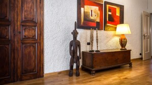 A wooden door, a wooden cabinet, and two abstract paintings on a textured wall. - Art Apartment with lake-view terrace, parking, and turkish bath. (Cernobbio)