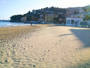 A sandy beach with footprints, a person walking, and buildings in the background. - Casa Rosa - Vacation apartments on the Flower Riviera, decorated with love (Diano San Pietro)