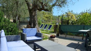 A patio with wicker furniture, including a sofa and two chairs, a small table, and a green garden bed in the background. - Casa Rosa - Vacation apartments on the Flower Riviera, decorated with love (Diano San Pietro)