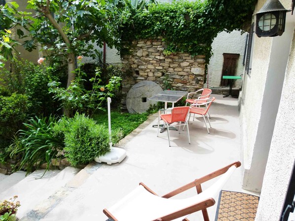 A patio with a stone wall, a table, and four chairs. - Casa Rosa - Vacation apartments on the Flower Riviera, decorated with love (Diano San Pietro)