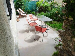 A patio with a table and chairs, surrounded by greenery and a stone wall. - Casa Rosa - Vacation apartments on the Flower Riviera, decorated with love (Diano San Pietro)