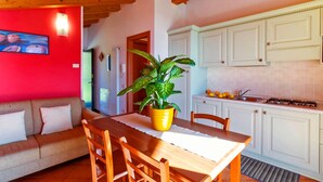 A cozy dining area with a wooden table and chairs, a sofa, and a potted plant. - Lake Como - Residence La Collina - Strawberry (Vercana)