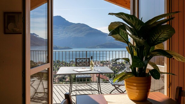 A balcony with a table, chairs, and a potted plant. - Lake Como - Residence La Collina - Strawberry (Vercana)
