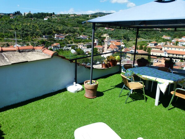 Un balcon avec du gazon synthétique, une table, des chaises et des plantes en pot.