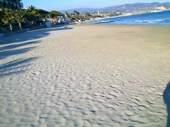 A beach with a clear view of the ocean and distant hills.