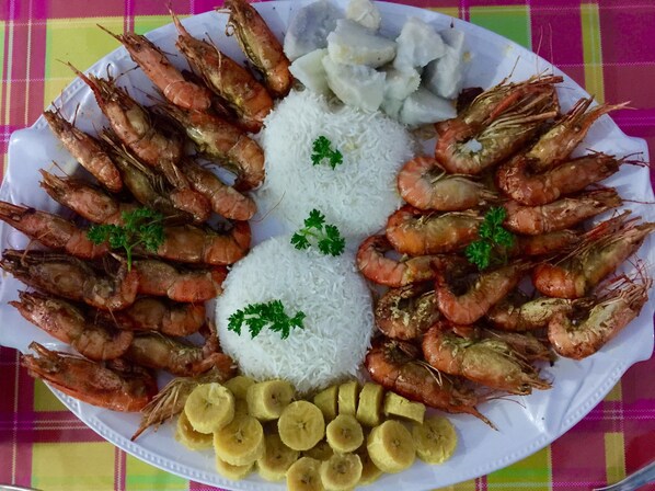 Une assiette de crevettes cuites, de riz blanc et de bananes coupées en tranches.