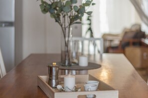 A wooden table with a tray containing a silver coffee pot, a white candle, and small decorative items.