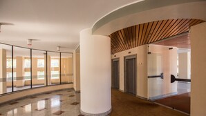 Et moderne interiør med en buet væg, en central hvid søjle og en glas elevator.