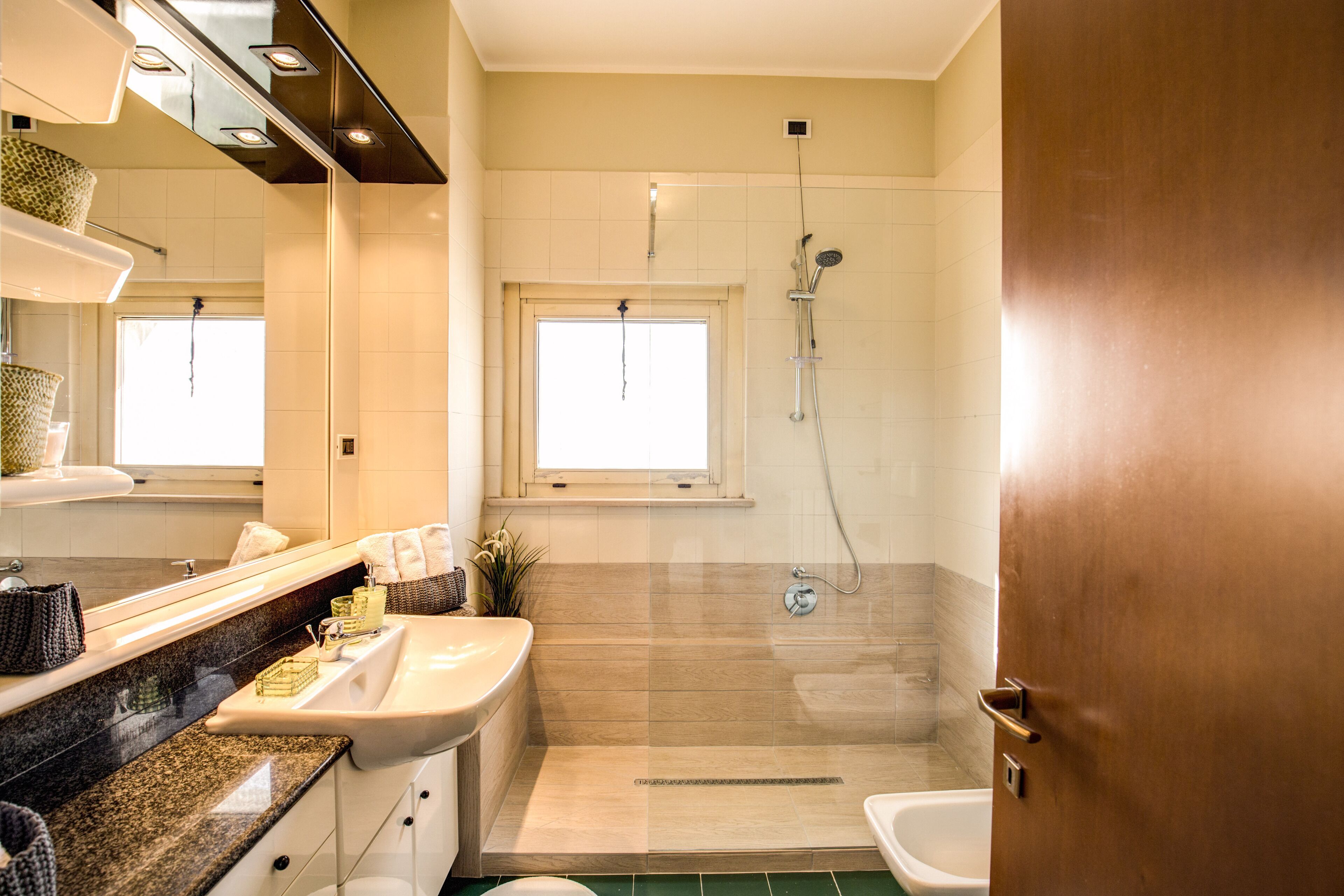 A bathroom with a sink, mirror, shower, and toilet.