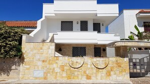 Ein modernes, zweistöckiges Haus mit Naturstein-Fassade, zahlreichen Fenstern und einem ehrwürdigen Eingangstor.