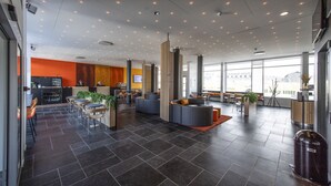 A modern lobby with dark tiled flooring, seating areas, and large windows offering views. - HHE Express Hotel (Nuuk)