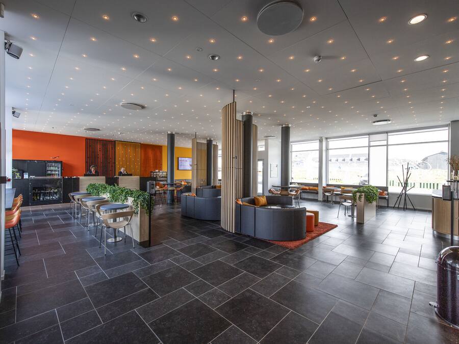 Eine moderne Lobby mit dunklen Fliesen, Sitzbereichen und großen Fenstern mit Blick.