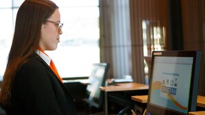 A person using a computer in a room with a window and a curtain. - HHE Express Hotel (Nuuk)