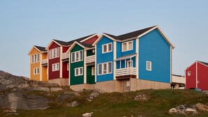 A row of colorful houses with a wooden deck and a rocky landscape. - HHE Express Hotel (Nuuk)