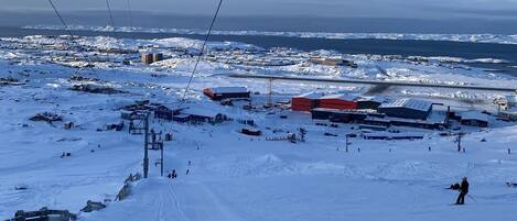 A snowy landscape with ski slopes, buildings, and a clear sky.