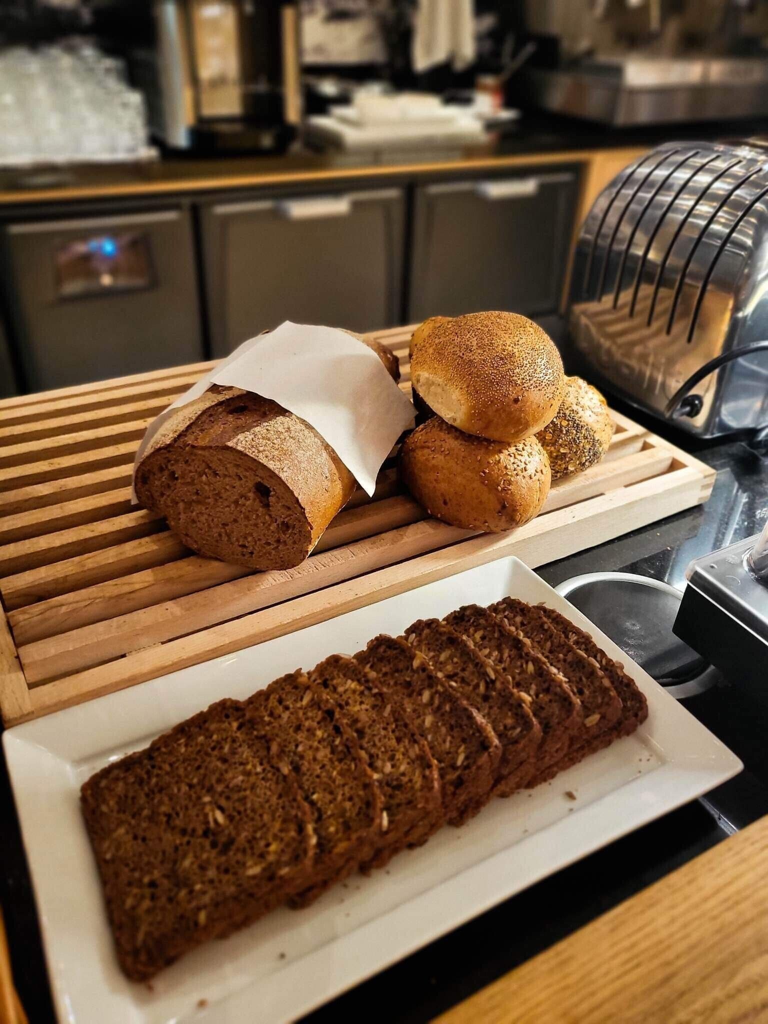 A kitchen counter with various breads and a loaf of sliced bread.