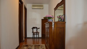 Un corridoio con un armadietto in legno, una sedia e un tappeto decorato.